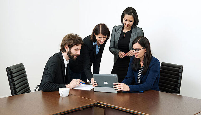 Four people gathering around a laptop.