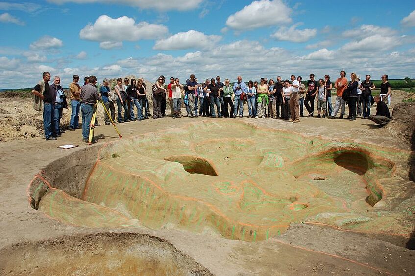 Picture shows people gathering around an excavation site.