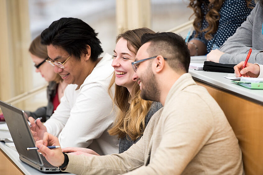 Students sitting in a lecture hall beaming with joy.