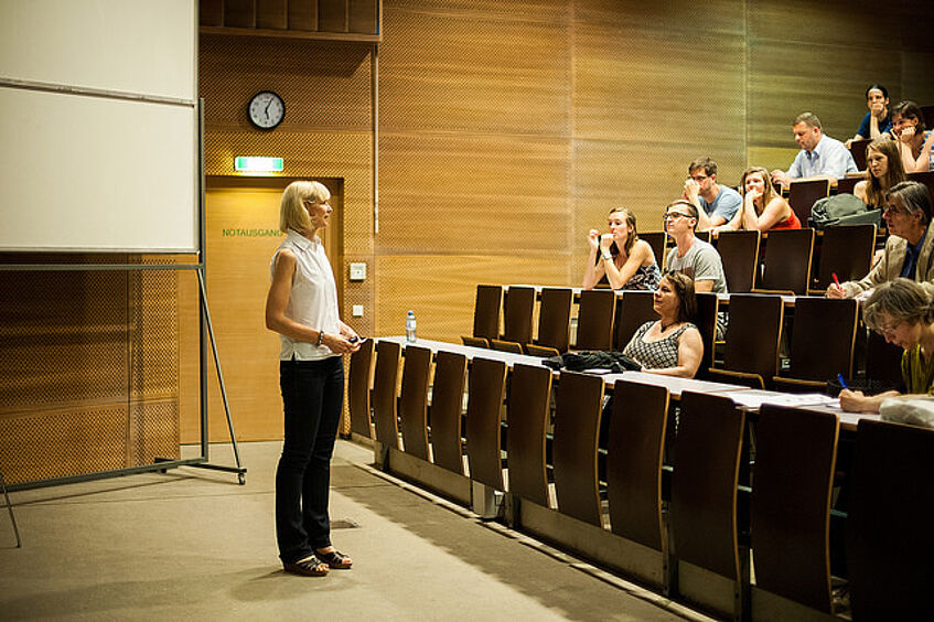 Picture shows lecturer and students in a lecture hall.