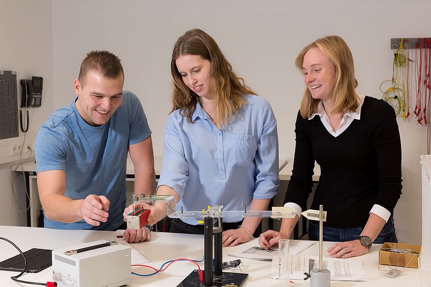 Drei Studierende der Physik bei einem Experiment.