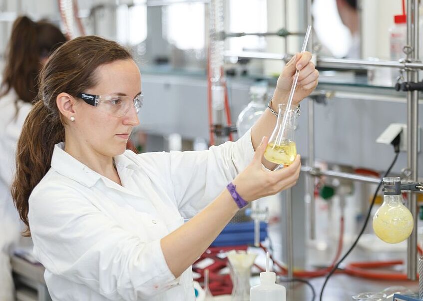 Student with protective glasses and vial.