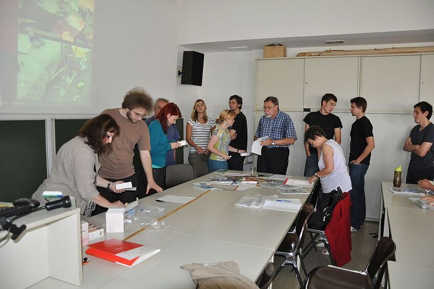 Students standing around a table and discussing.