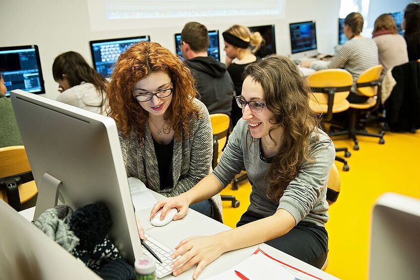 Zwei Studentinnen sitzen bei einem Computer.