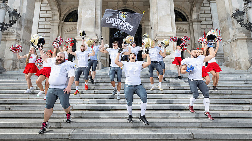Football team and cheerleader on the stairs of the main entrance to the university