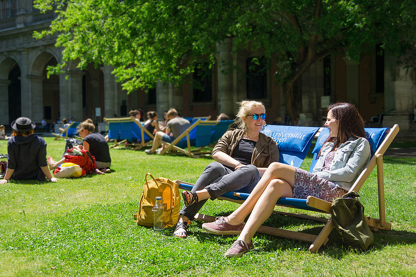 Students sit in deck chairs in the arcaded courtyard.