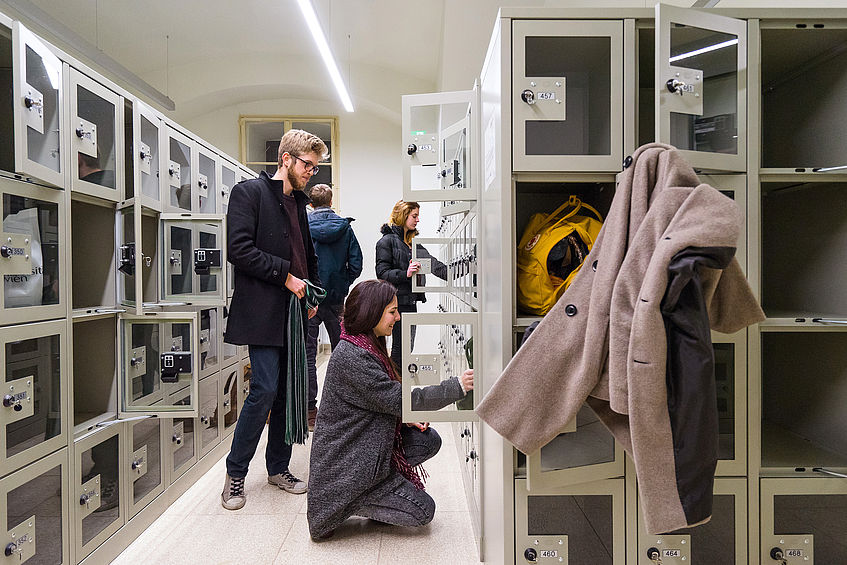 Studierende stehen vor den Garderobenkästen.